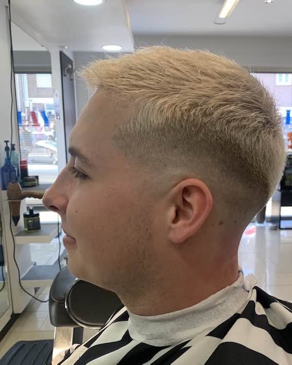 Kort geblondeerd kapsel met een skin fade, van opzij gezien
